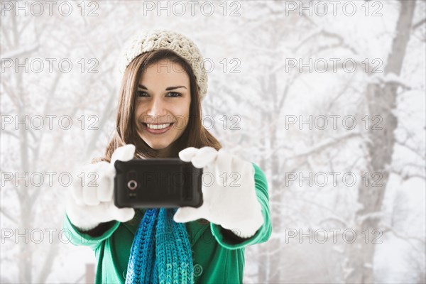 Caucasian woman taking pictures in snow