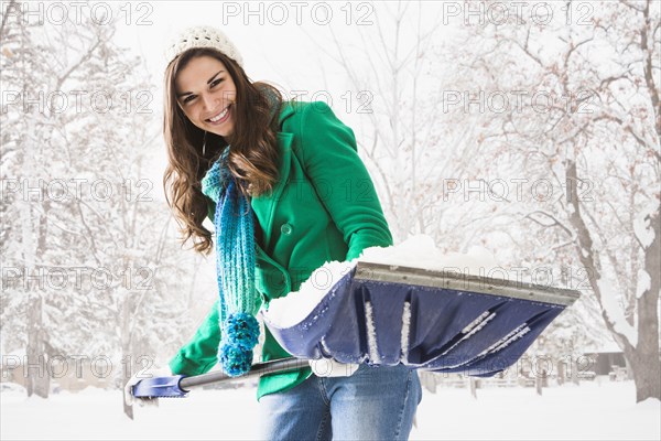 Caucasian woman shoveling snow outdoors