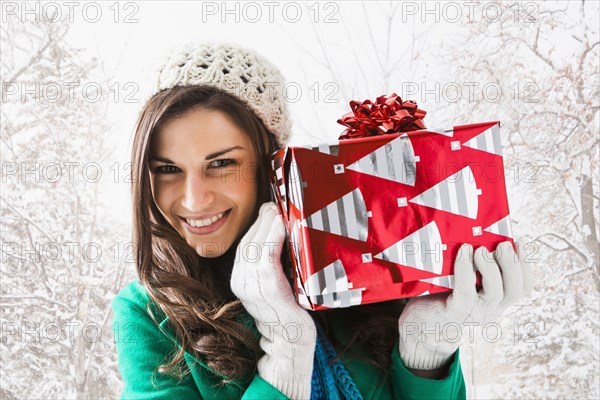 Caucasian woman holding Christmas gift in snow