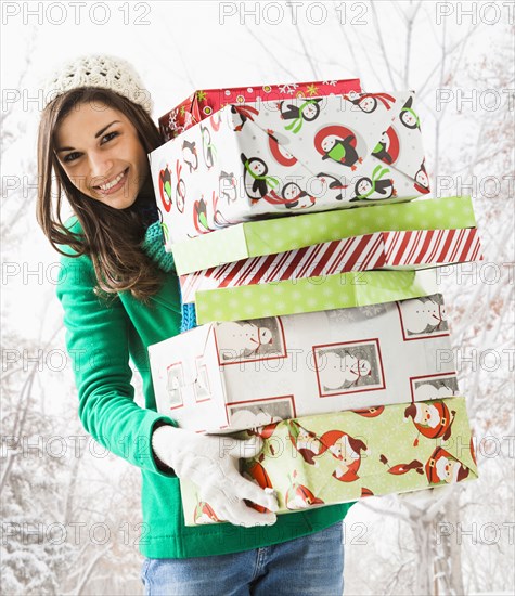 Caucasian woman holding Christmas gifts in snow