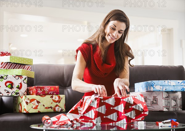 Caucasian woman wrapping Christmas presents in living room