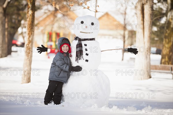 Caucasian boy building snowman in snow
