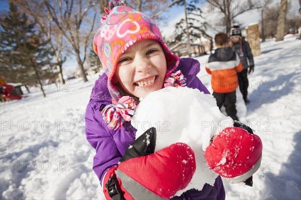 Caucasian girl holding snowball outdoors