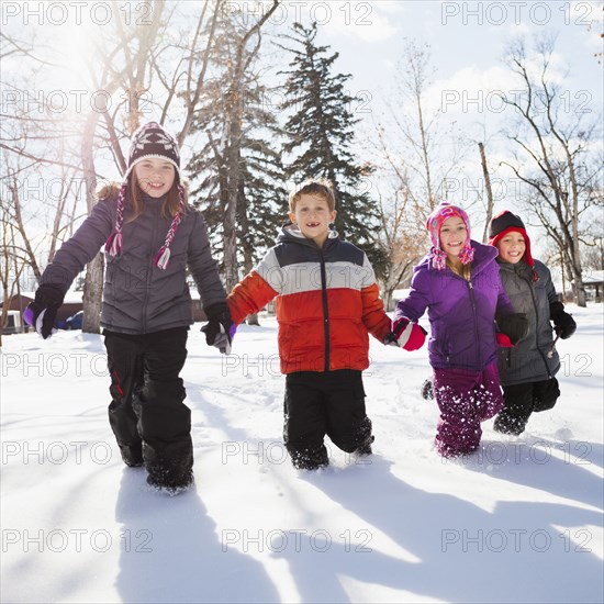 Caucasian children walking in snow outdoors