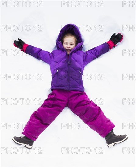 Caucasian girl making snow angel outdoors