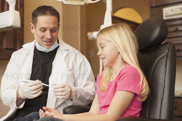 Caucasian dentist talking to girl in office