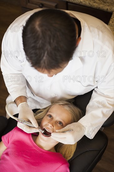 Dentist examining girl's teeth in office