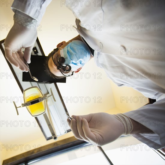 Caucasian dentist towering over patient in office