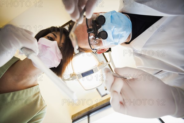 Dentist and nurse towering over patient in office