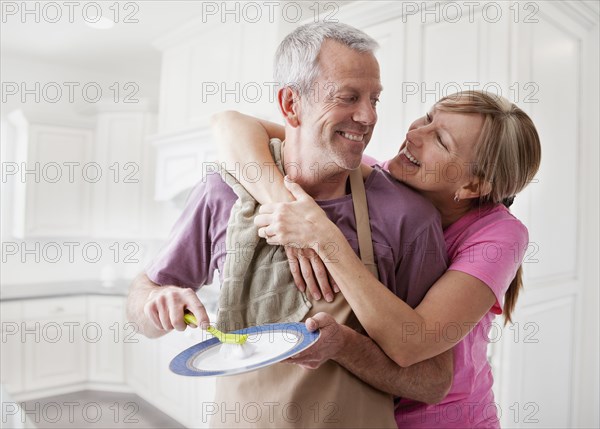 Caucasian couple washing dishes in kitchen