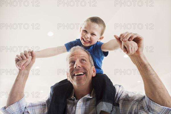 Caucasian man carrying son on shoulders