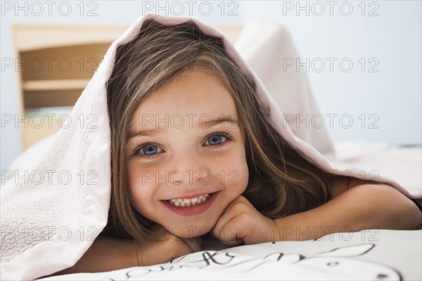 Caucasian girl smiling under covers
