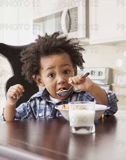 Mixed race boy eating at table