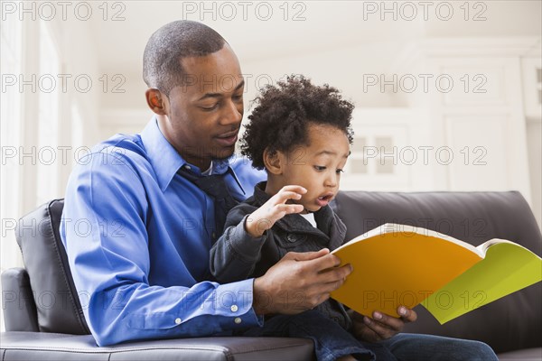 Father and son reading on sofa