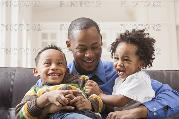 Father and sons relaxing on sofa