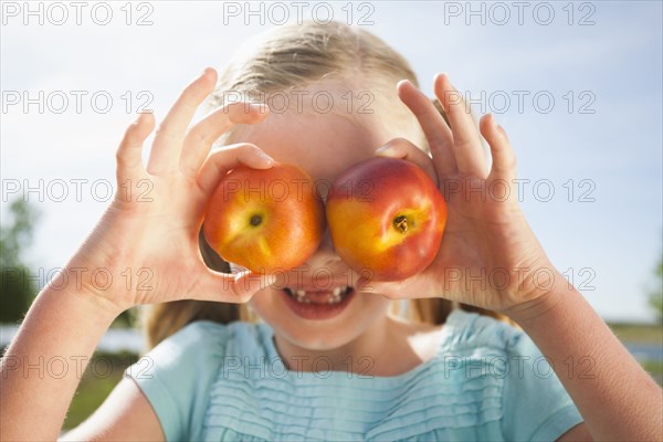 Caucasian girl holding fruit over eyes