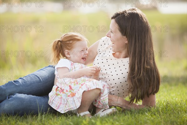 Caucasian mother and baby relaxing in grass