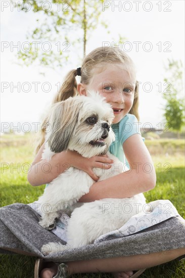 Caucasian girl hugging dog in grass