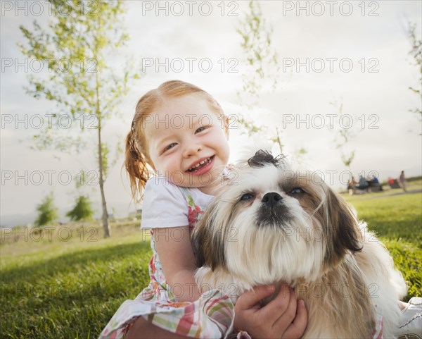 Caucasian girl hugging dog in grass