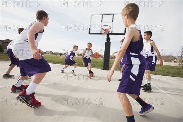 Caucasian boys playing basketball on court