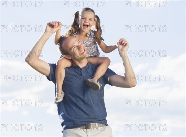 Caucasian father carrying daughter on shoulders