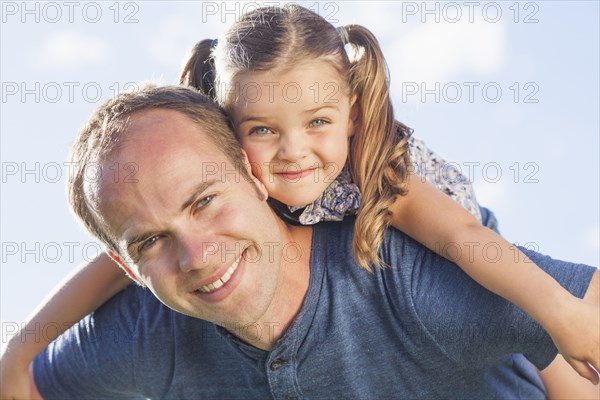 Caucasian father carrying daughter on shoulders