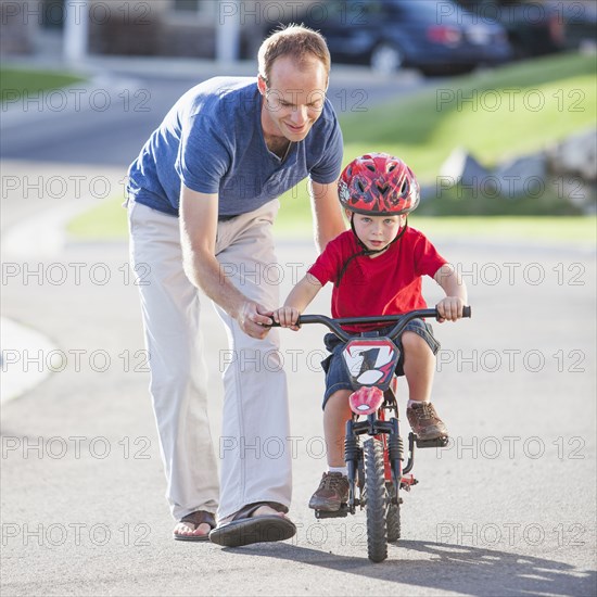 Caucasian father teaching son to ride bicycle