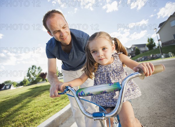 Caucasian father teaching daughter to ride bicycle