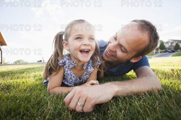 Caucasian father and daughter laying in grass