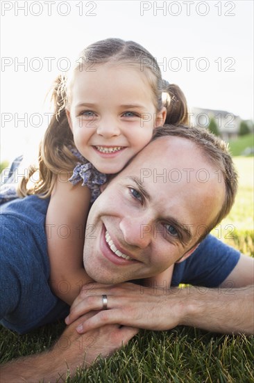 Caucasian father and daughter laying in grass