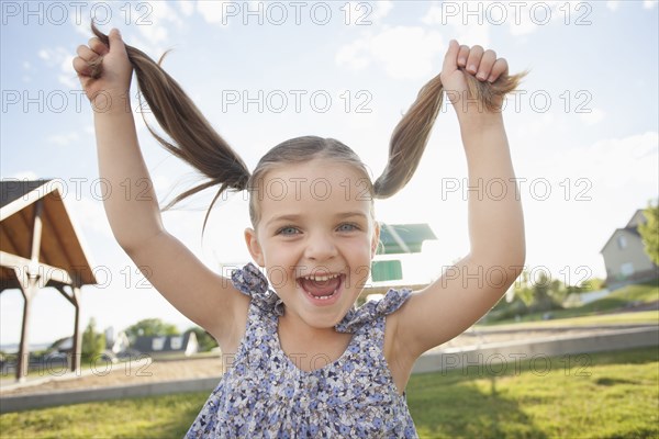 Caucasian girl playing with pigtails outdoors