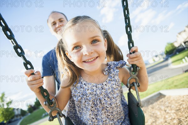 Caucasian father pushing daughter on swing