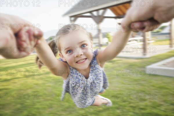 Caucasian father spinning daughter in park