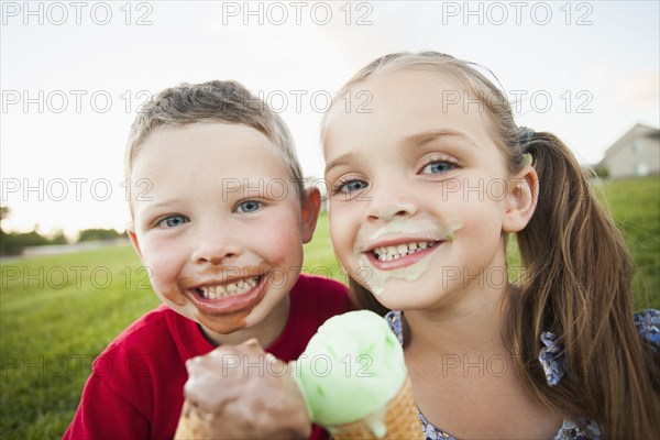 Caucasian children eating ice cream outdoors