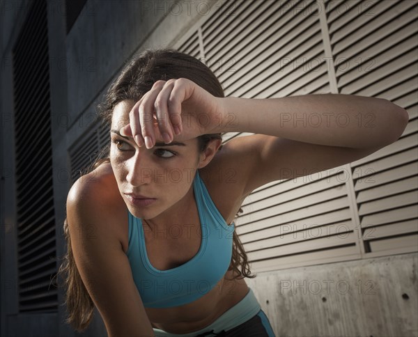 Caucasian runner wiping sweat off forehead