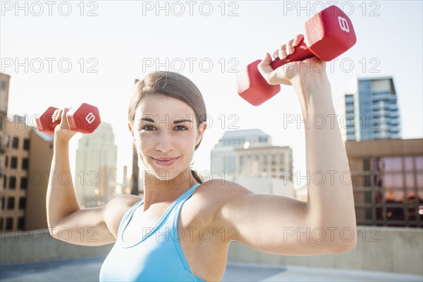 Caucasian woman lifting dumbbells on urban rooftop