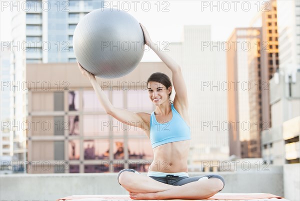 Caucasian woman using fitness ball on urban rooftop
