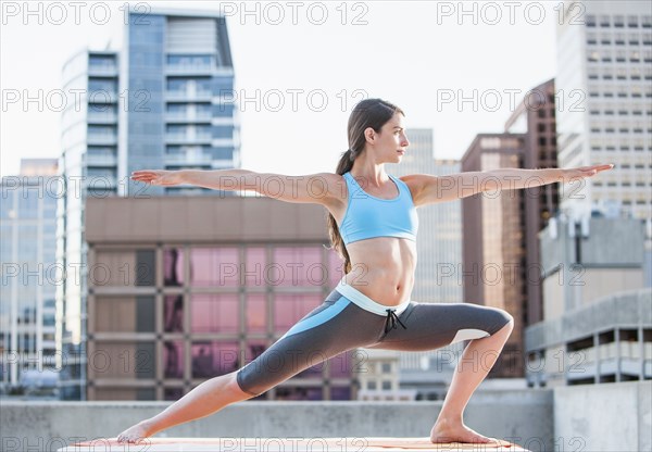 Caucasian woman practicing yoga on urban rooftop