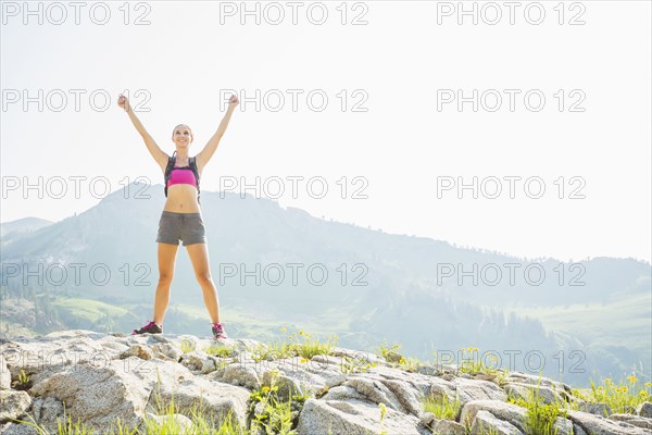 Caucasian woman cheering on rocky hilltop