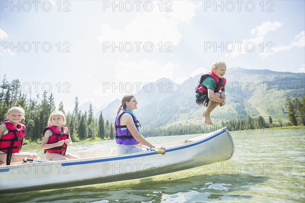 Caucasian boy jumping from canoe into lake