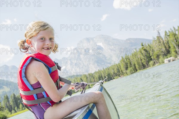 Caucasian girl sitting in canoe on lake