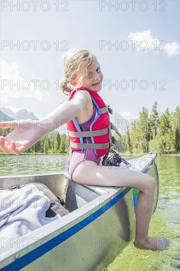 Caucasian girl sitting on top of canoe on lake