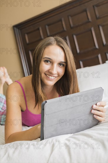 Caucasian woman using digital tablet in bed