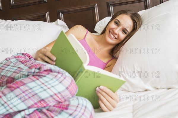 Caucasian woman reading in bed