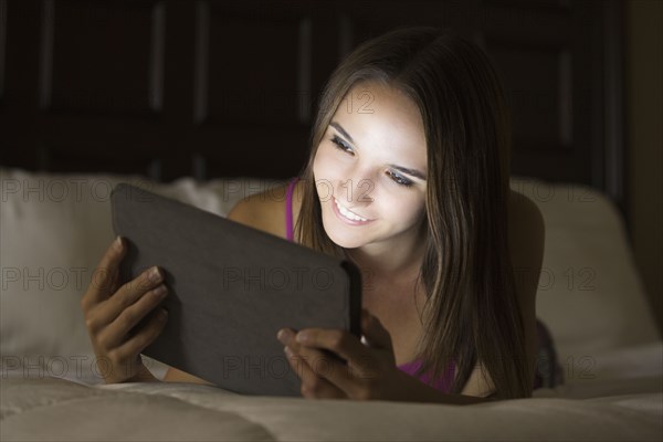 Caucasian woman using digital tablet in bed