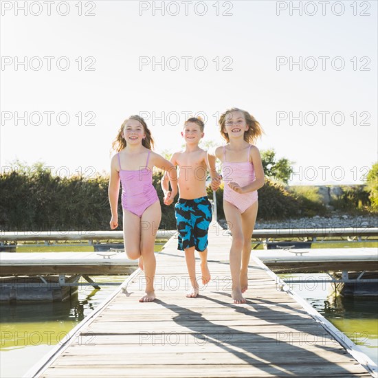Caucasian children running on dock
