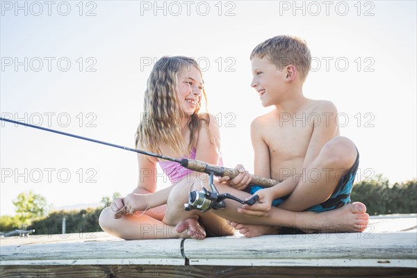 Caucasian children fishing off dock