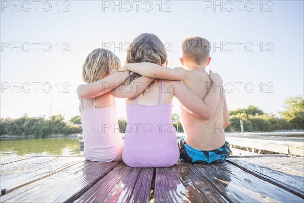 Caucasian children sitting on dock