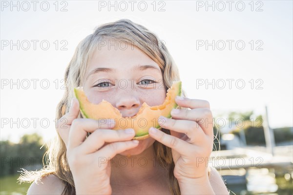 Caucasian girl eating cantaloupe slice