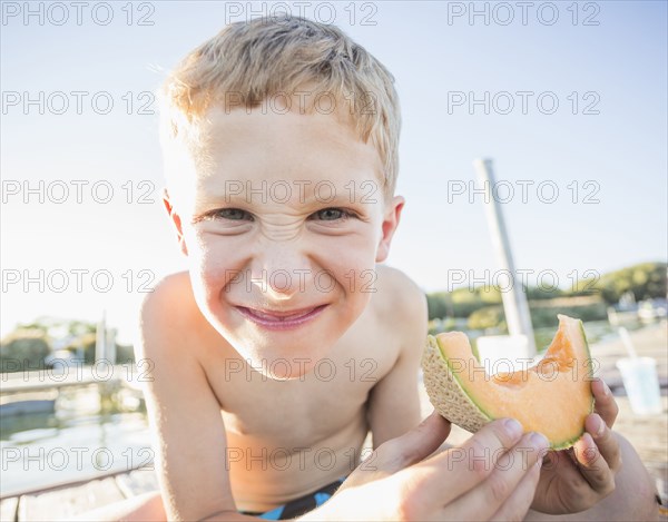 Caucasian boy eating cantaloupe slice